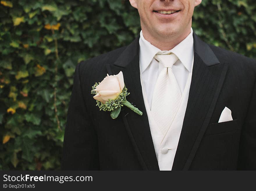 Man in Black Formal Suit With White Necktie Beside Green Bush in Shallow Focus Photography