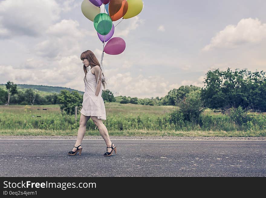 A sad woman is walking with a bunch of balloons. A sad woman is walking with a bunch of balloons.