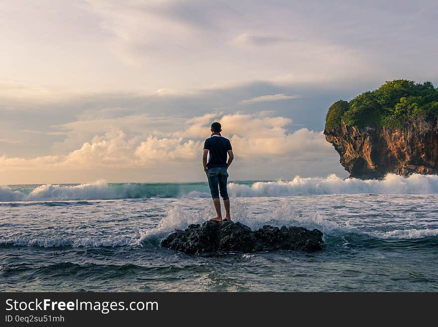 Man Standing on Stone Near Seashore during Sunrise Photography