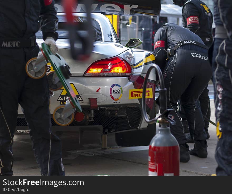 Man in Black Suit Repairing Grey Car