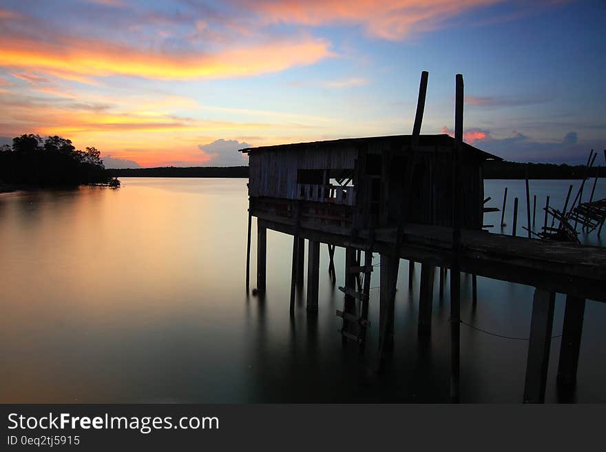 Silhouette of House on Top of Ocean Water during Sunset