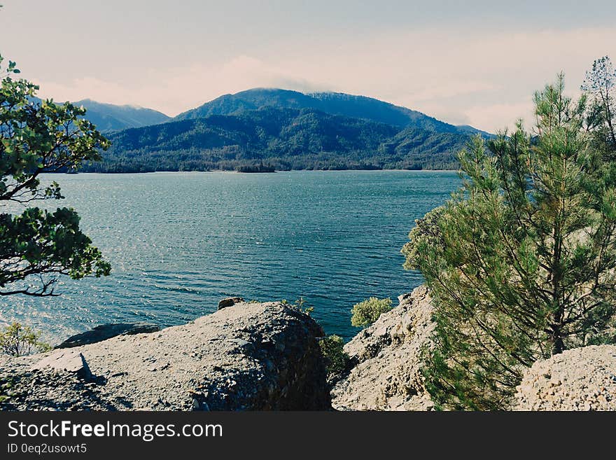 A view over a blue lake from rocks at the shore and hills on the distance. A view over a blue lake from rocks at the shore and hills on the distance.