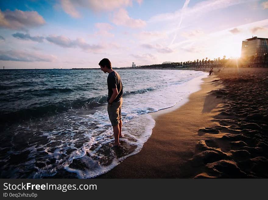 A man standing at the seashore watching the sea. A man standing at the seashore watching the sea.