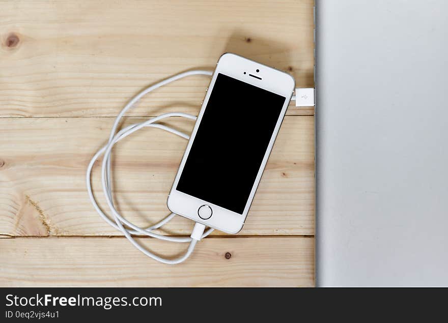 A smartphone on a table with the charging connector next to it. A smartphone on a table with the charging connector next to it.