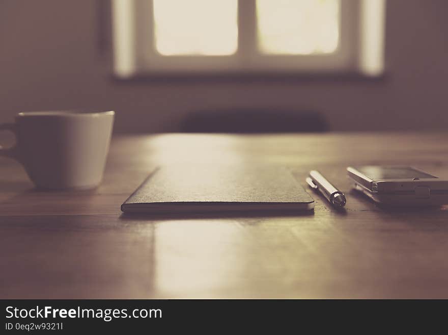 Working desk with notebook, pen and smartphone next to a coffee cup