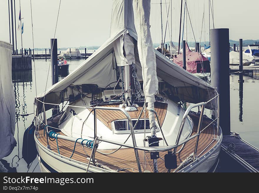 White and Brown Boat on Dock Near Speed Boat