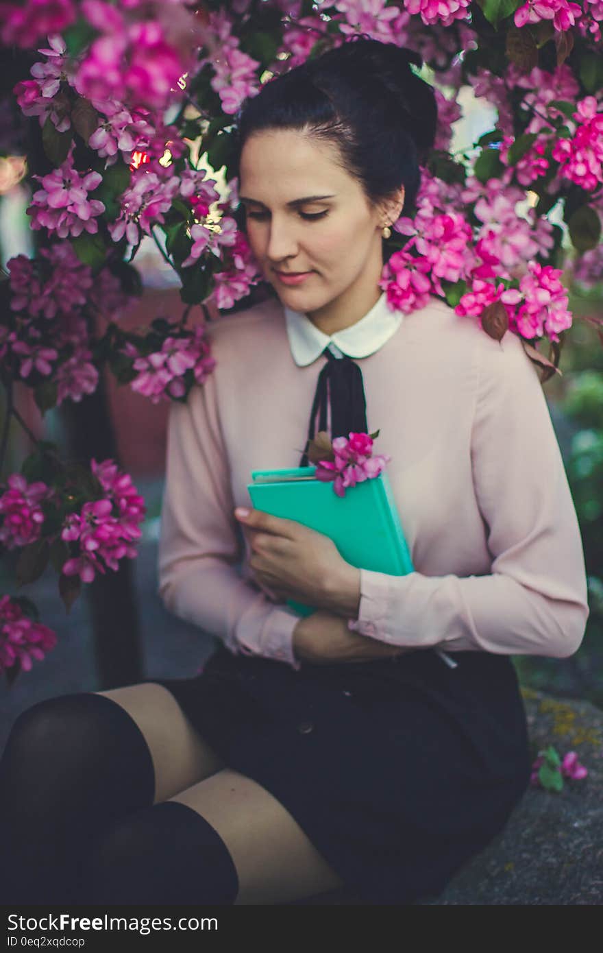 Woman Wearing Beige Long Sleeve Shirt Sitting Beside Purple Petaled Flower