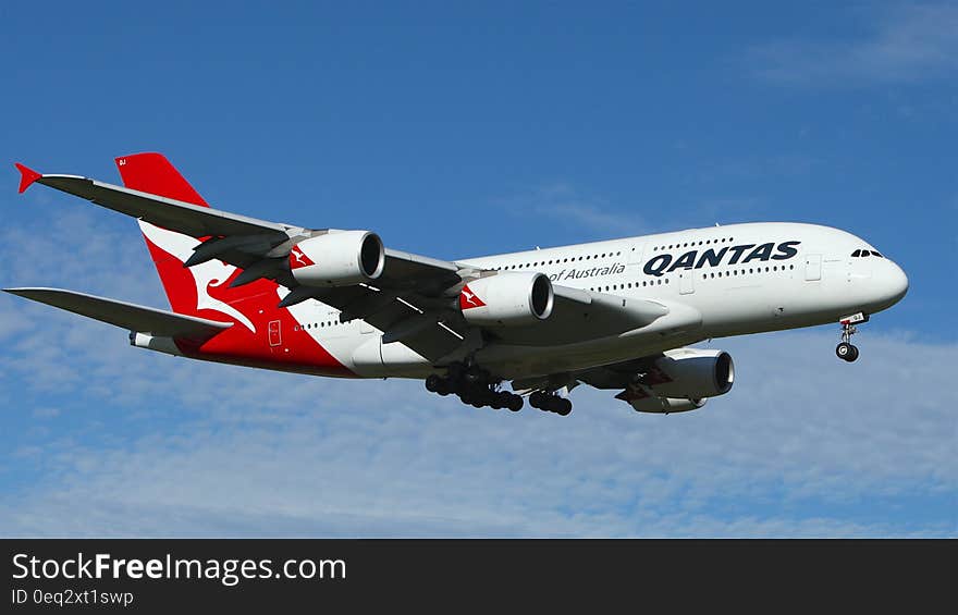 White and Red Qantas Airplane Fly High Under Blue and White Clouds