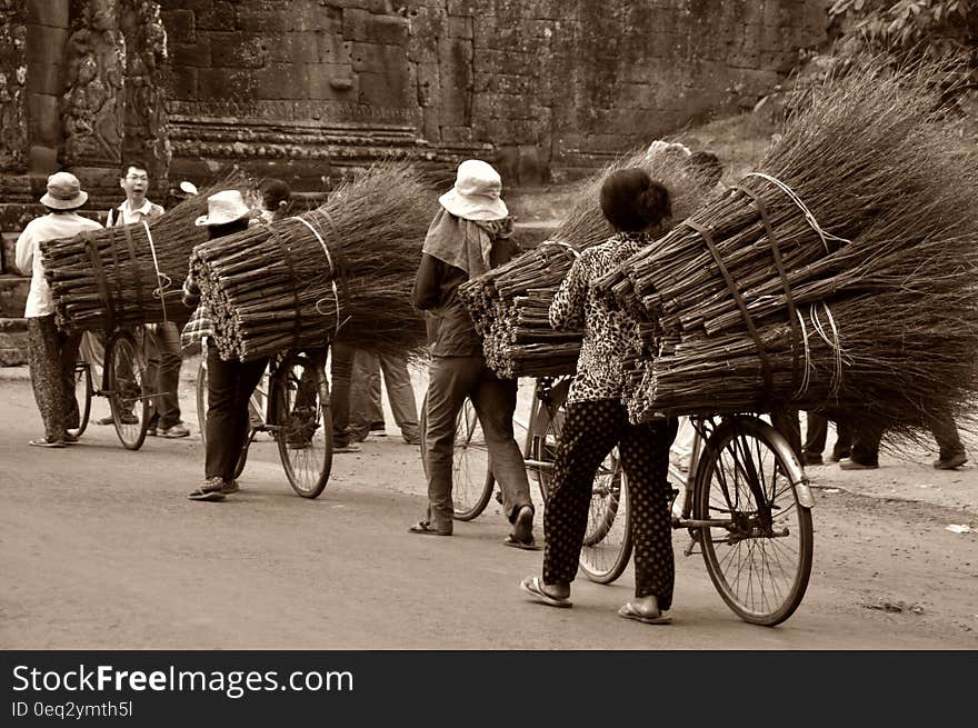 Asian workers transporting brooms on bicycles on the road