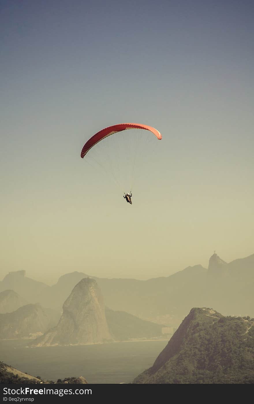 Person in Parachute Gliding Above Mountains