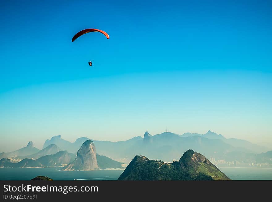 Panorama Photo of a Person Parachuting Above Volcano Lake during Daytime