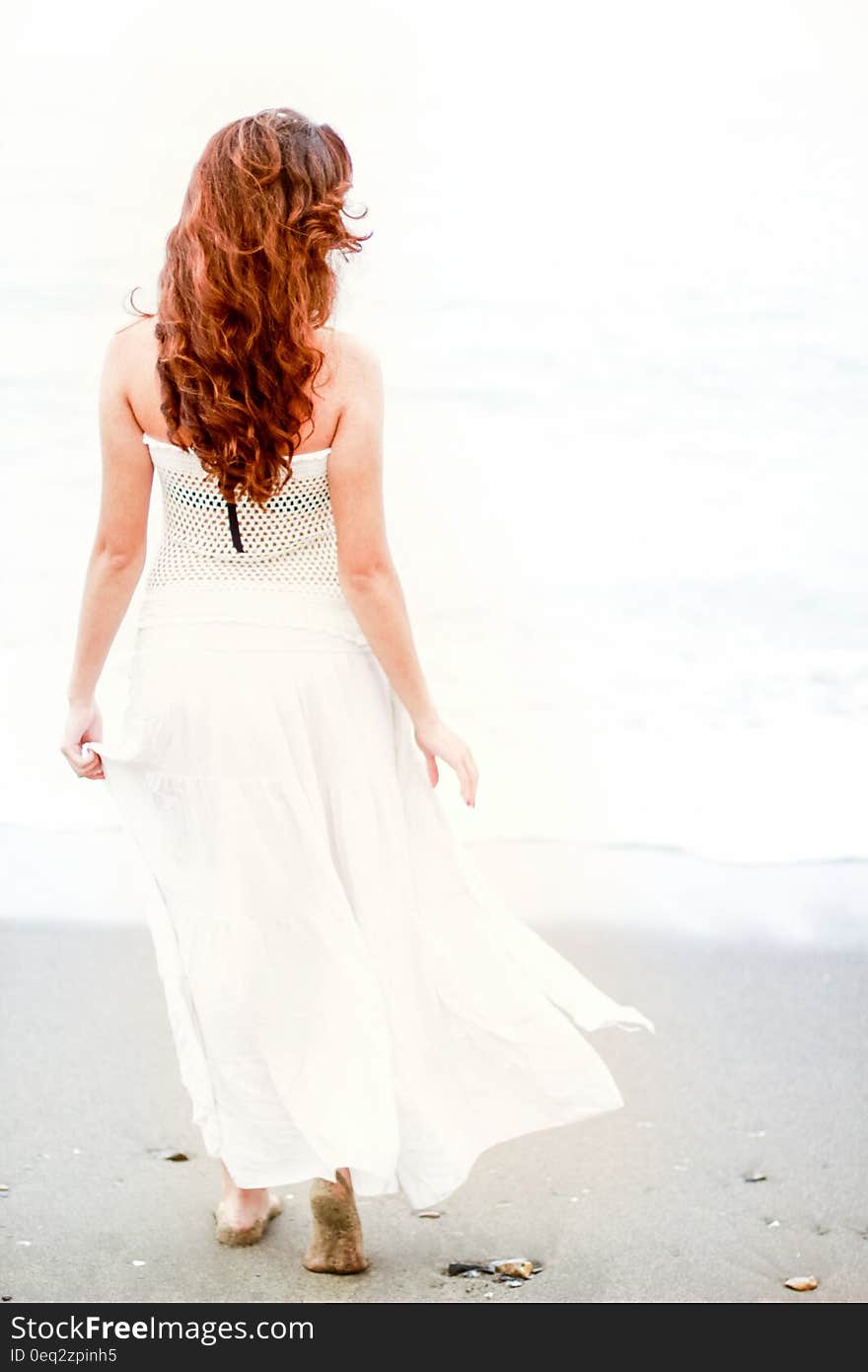 Redhead woman walking on the beach on a sunny summer day. Redhead woman walking on the beach on a sunny summer day.