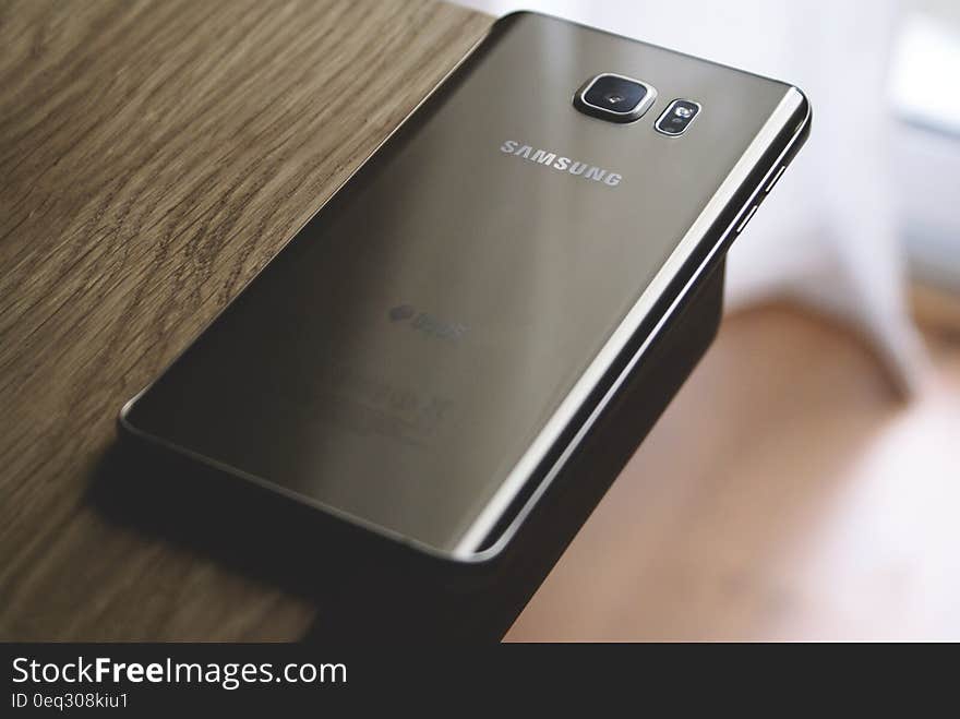 Silver Samsung Galaxy Smartphone on Top of Brown Wooden Table