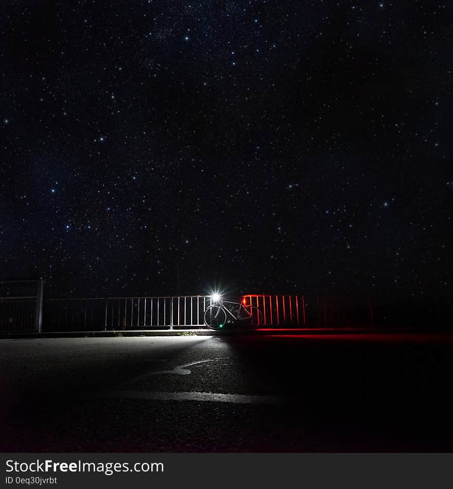 Bicycle leaning against railing with starry night sky in the background. Bicycle leaning against railing with starry night sky in the background.