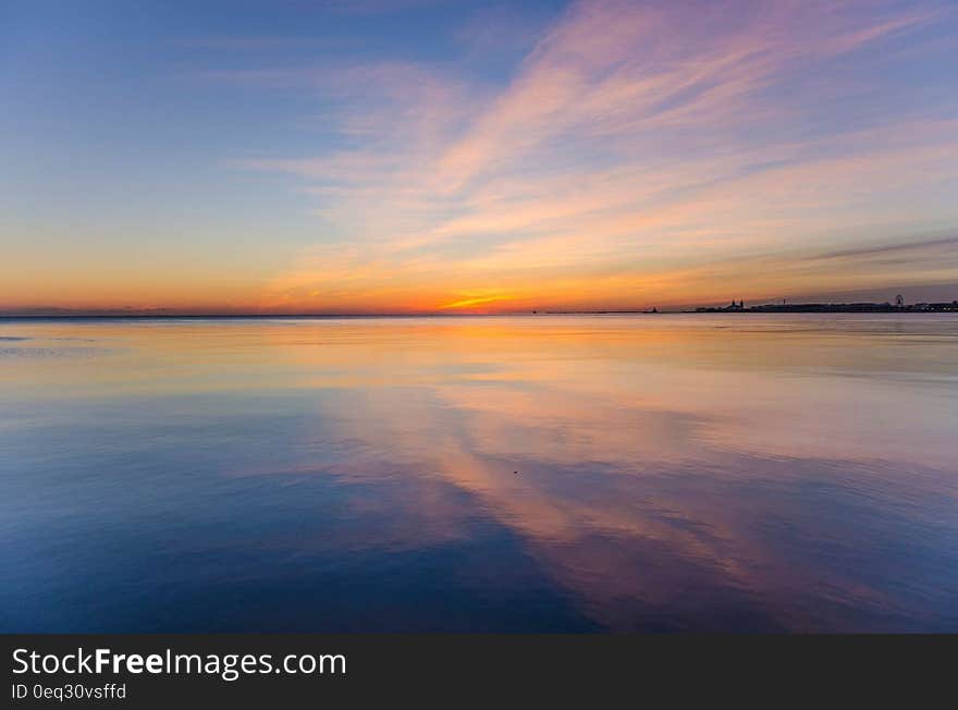 A view of a sunset or sunrise in the distance, in the middle of the ocean.