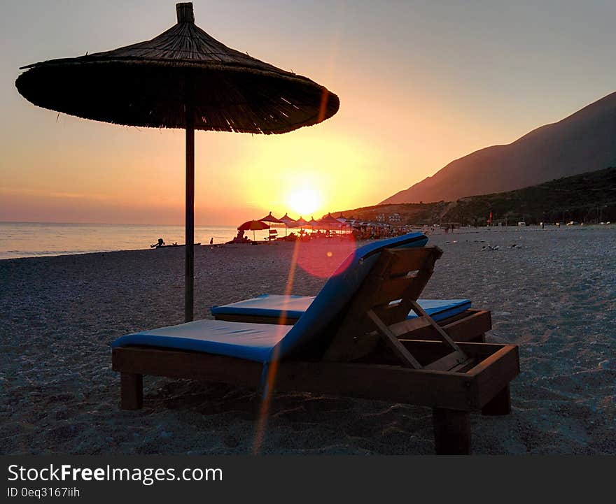 Brown Wooden Lounger on Seashore during Day Time