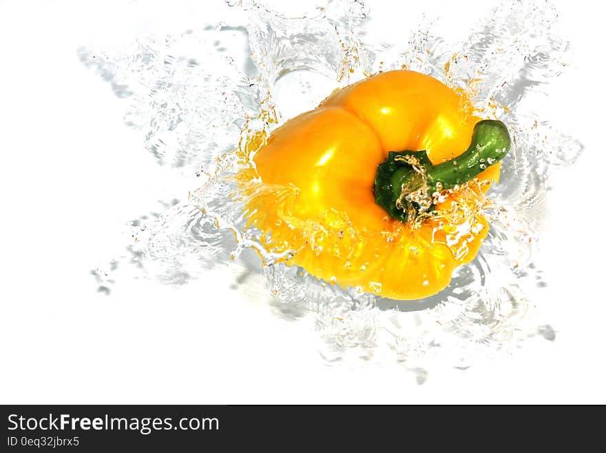 Yellow bell pepper splashing as it drops into water. Yellow bell pepper splashing as it drops into water.