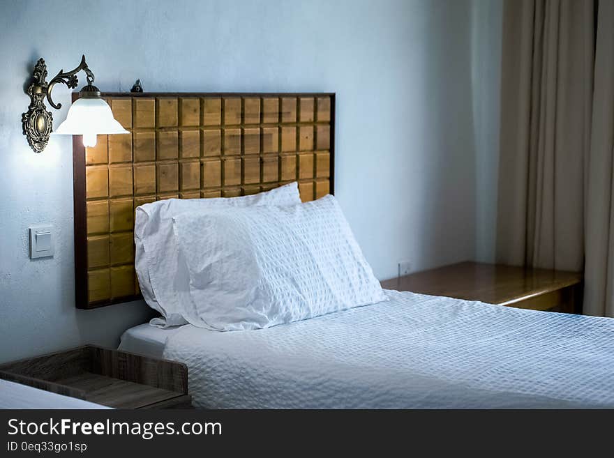 White Bedding Cover Beside Brown Wooden Side Table