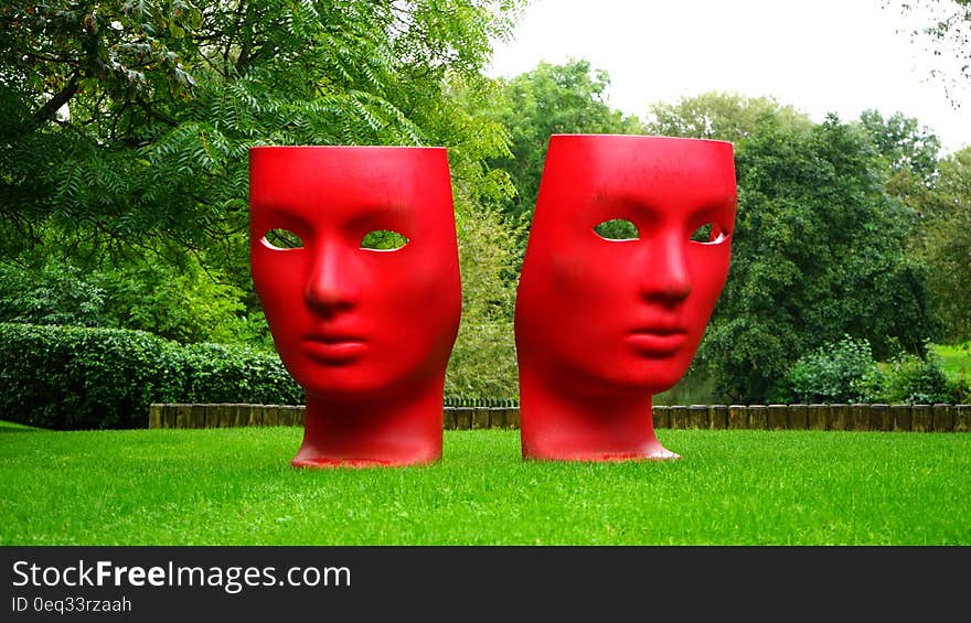 Red Human Face Monument on Green Grass Field