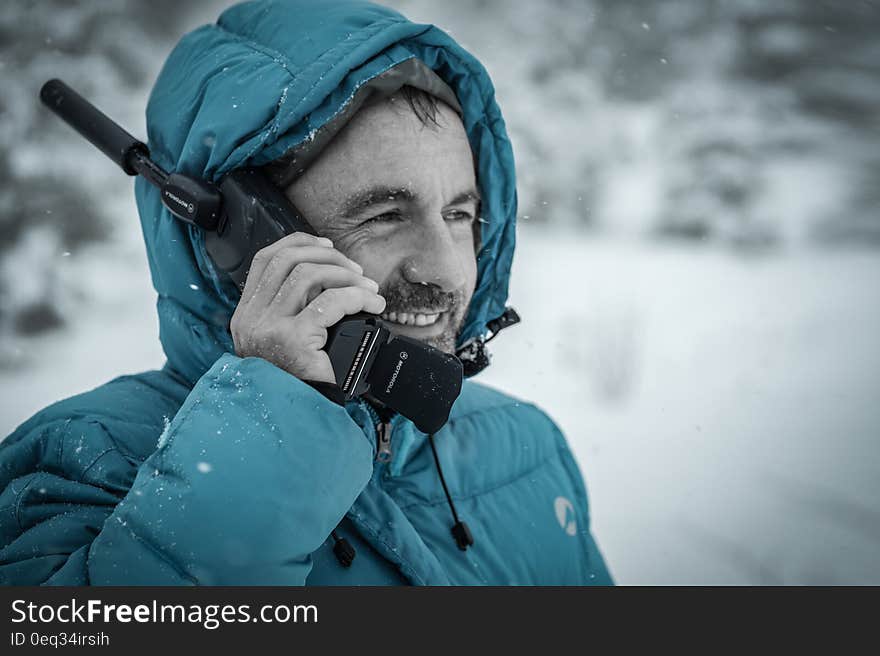 Man in Blue Hoodie Jacket Holding Black Radio Receiver during Snowy Day Time