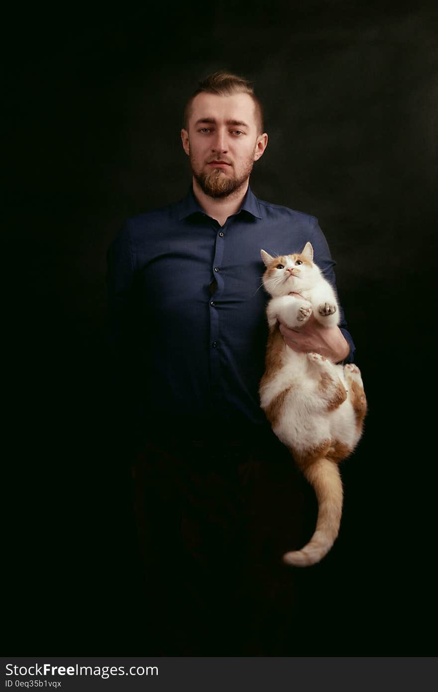 Man in Grey Dress Shirt Holding White and Orange Fur Cat