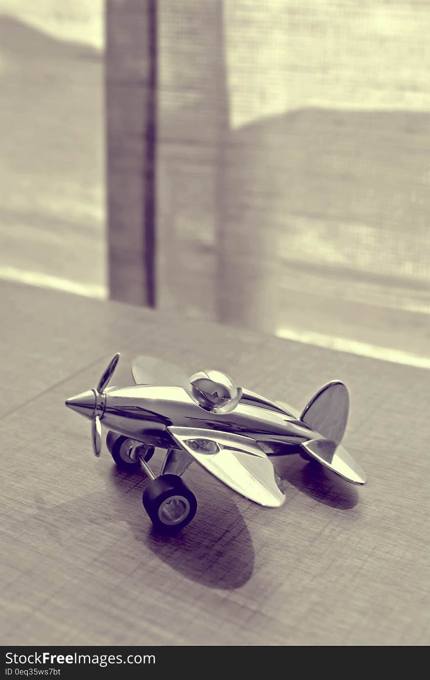 Sepia Photography of Stainless Steel Biplane on Brown Wooden Table Near Window during Daytime