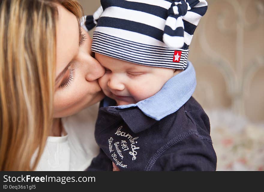 Woman in White Shirt Kissing Baby With Black and White Stripe Knit Cap