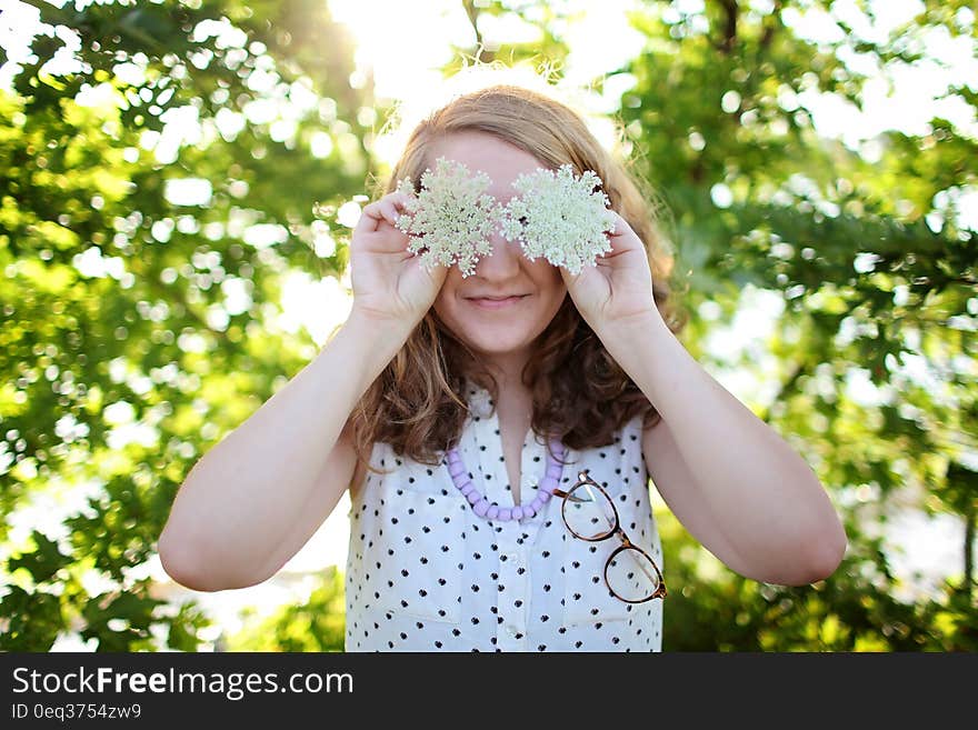 Woman Wearing White and Black Dotted Sleeveless Top Holding White Flower