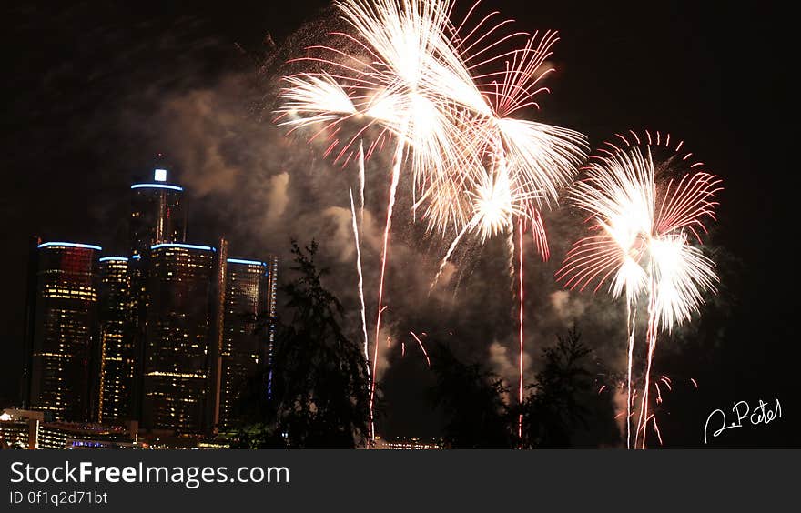 Fireworks display against city skyline illuminated at night. Fireworks display against city skyline illuminated at night.