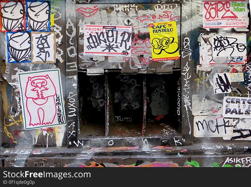 sticker-and-graffiti-covered wall with openings