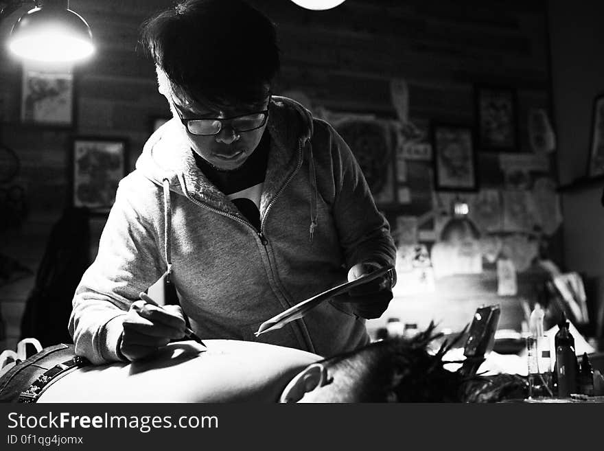 Black and white portrait of a tattoo artist working on man's back. Black and white portrait of a tattoo artist working on man's back.