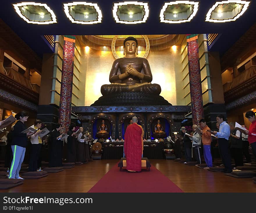 Worshipers and monk inside temple praying to Buddha statue. Worshipers and monk inside temple praying to Buddha statue.