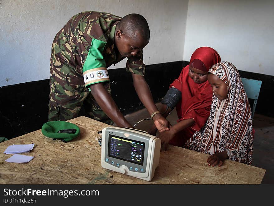 A Kenyan medical officer takes a woman&#x27;s blood pressure at a free medical clinic provided by the Kenyan Contingent serving with the African Union Mission in Somalia &#x28;AMISOM&#x29; in the southern Somali port city of Kismayo, 19 August 2013. Open 7 days a week and seeing an average of 80 patients a day from Kismayo and surrounding villages, AMISOM medical staff provide the free health care to Kismayo&#x27;s civilians, treating a variety of cases including malaria, respiratry tract infections, sexually transmitted infections and occassionally gunshot wounds. AU-UN IST PHOTO / RAMADAAN MOHAMED HASSAN. A Kenyan medical officer takes a woman&#x27;s blood pressure at a free medical clinic provided by the Kenyan Contingent serving with the African Union Mission in Somalia &#x28;AMISOM&#x29; in the southern Somali port city of Kismayo, 19 August 2013. Open 7 days a week and seeing an average of 80 patients a day from Kismayo and surrounding villages, AMISOM medical staff provide the free health care to Kismayo&#x27;s civilians, treating a variety of cases including malaria, respiratry tract infections, sexually transmitted infections and occassionally gunshot wounds. AU-UN IST PHOTO / RAMADAAN MOHAMED HASSAN.