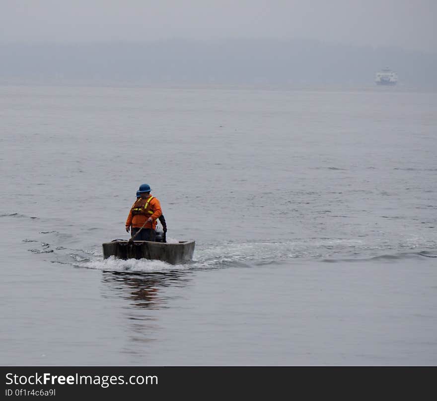 Man in wooden boat on water in fog. Man in wooden boat on water in fog.