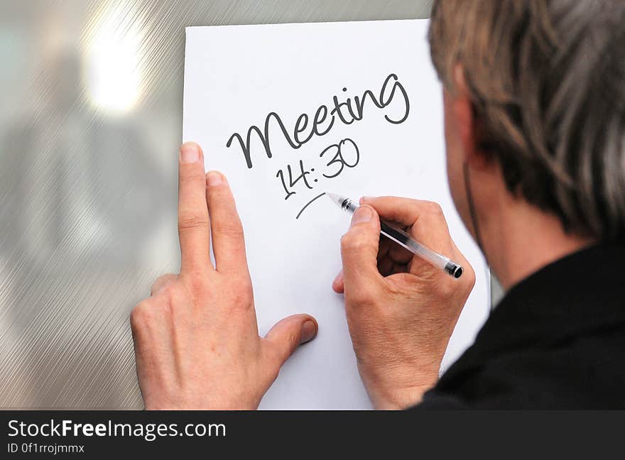 A man writing a note about meeting. A man writing a note about meeting.