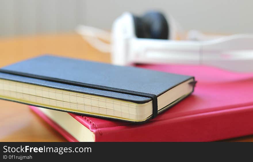 A notebook on the desk with other books and headphones. A notebook on the desk with other books and headphones.