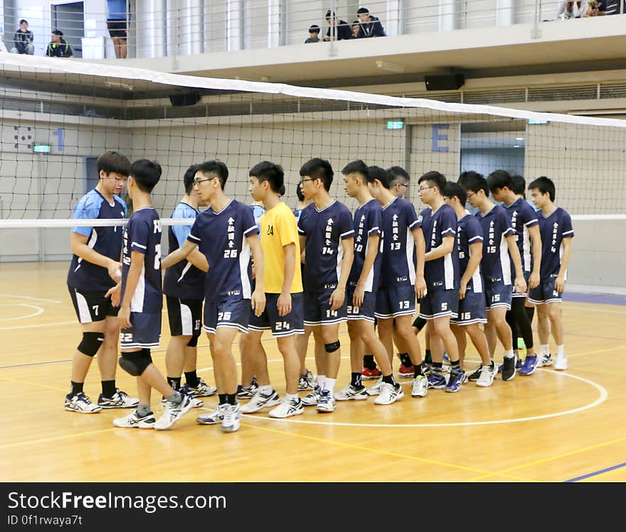 Teams greeting on court during youth volleyball game.