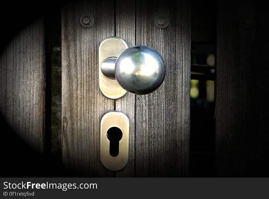 A close up of a knob and a keyhole on a wooden door. A close up of a knob and a keyhole on a wooden door.