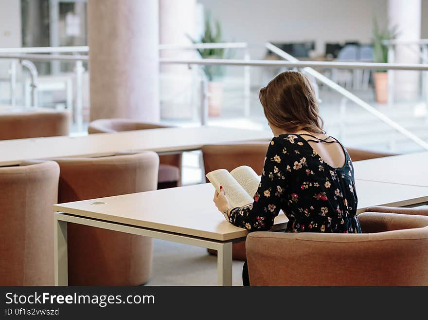 A woman reading a book at a table. A woman reading a book at a table.