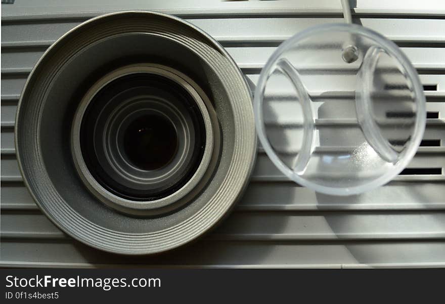 A close up of a video projector lens and lens cover. A close up of a video projector lens and lens cover.