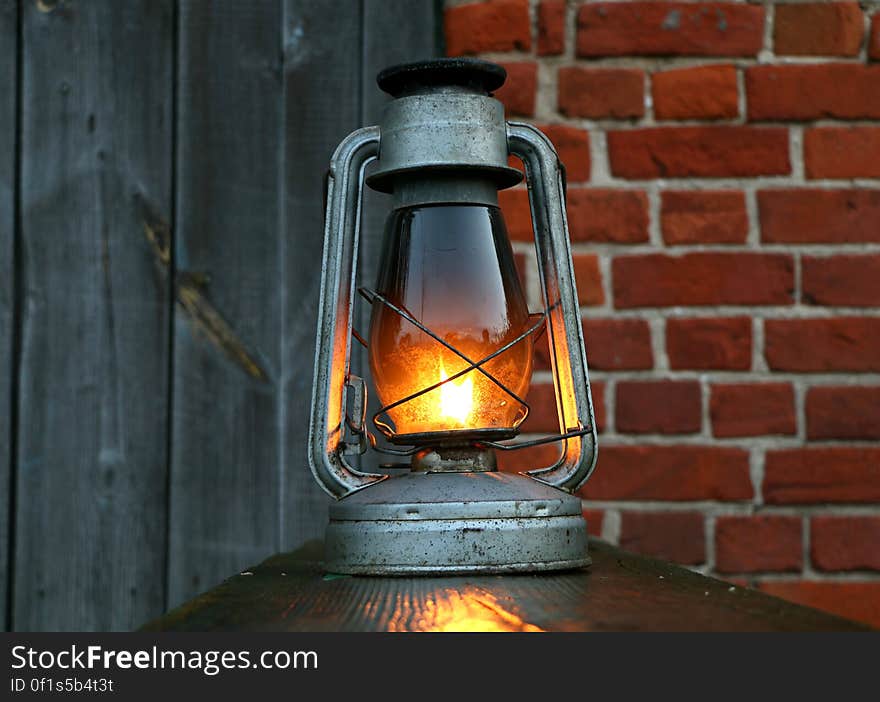 A metallic lantern lit on a railing. A metallic lantern lit on a railing.