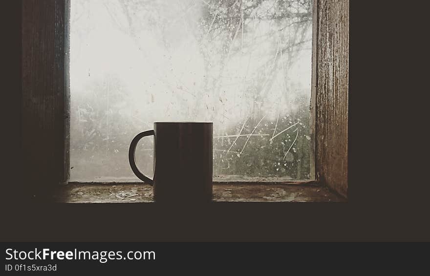 A mug sitting on a window sill. A mug sitting on a window sill.