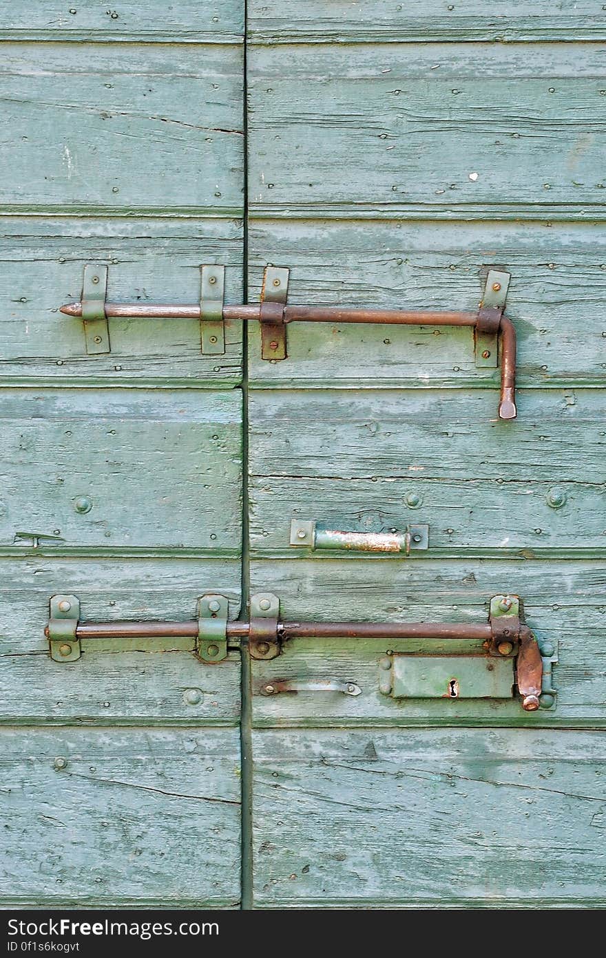 Ancient green door with old fashioned system of locks and bolts and paint peeling off. Ancient green door with old fashioned system of locks and bolts and paint peeling off.