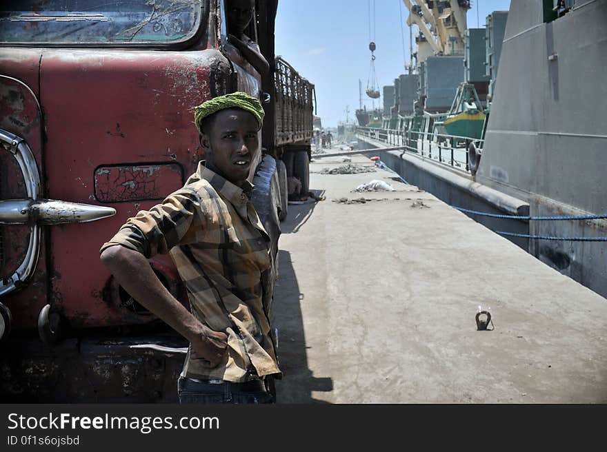 Man standing next to red truck on streets. Man standing next to red truck on streets.