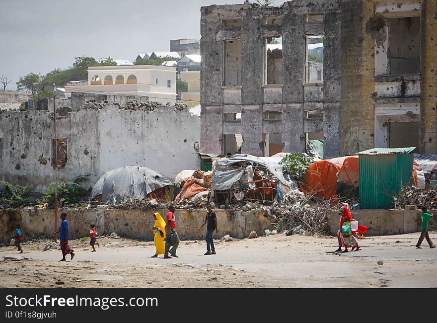 Civilians walk past bombed-out and destroyed buildings in the Boondheere district of the Somali capital Mogadishu, 05 August, 2013. 06 August marks 2 years since the Al Qaeda-affiliated extremist group Al Shabaab withdrew from Mogadishu following sustained operations by forces of the Somali National Army &#x28;SNA&#x29; backed by troops of the African Union Mission in Somalia &#x28;AMISOM&#x29; to retake the city. Since the group&#x27;s departure the country&#x27;s captial has re-established itself and a sense of normality has returned. Buildings and infrastructure devastated and destroyed by two decades of conflict have been repaired; thousands of Diaspora Somalis have returned home to invest and help rebuild their nation; foreign embassies and diplomatic missions have reopened and for the first time in many years, Somalia has an internationally recognised government.. AU-UN IST PHOTO / STUART PRICE. Civilians walk past bombed-out and destroyed buildings in the Boondheere district of the Somali capital Mogadishu, 05 August, 2013. 06 August marks 2 years since the Al Qaeda-affiliated extremist group Al Shabaab withdrew from Mogadishu following sustained operations by forces of the Somali National Army &#x28;SNA&#x29; backed by troops of the African Union Mission in Somalia &#x28;AMISOM&#x29; to retake the city. Since the group&#x27;s departure the country&#x27;s captial has re-established itself and a sense of normality has returned. Buildings and infrastructure devastated and destroyed by two decades of conflict have been repaired; thousands of Diaspora Somalis have returned home to invest and help rebuild their nation; foreign embassies and diplomatic missions have reopened and for the first time in many years, Somalia has an internationally recognised government.. AU-UN IST PHOTO / STUART PRICE.