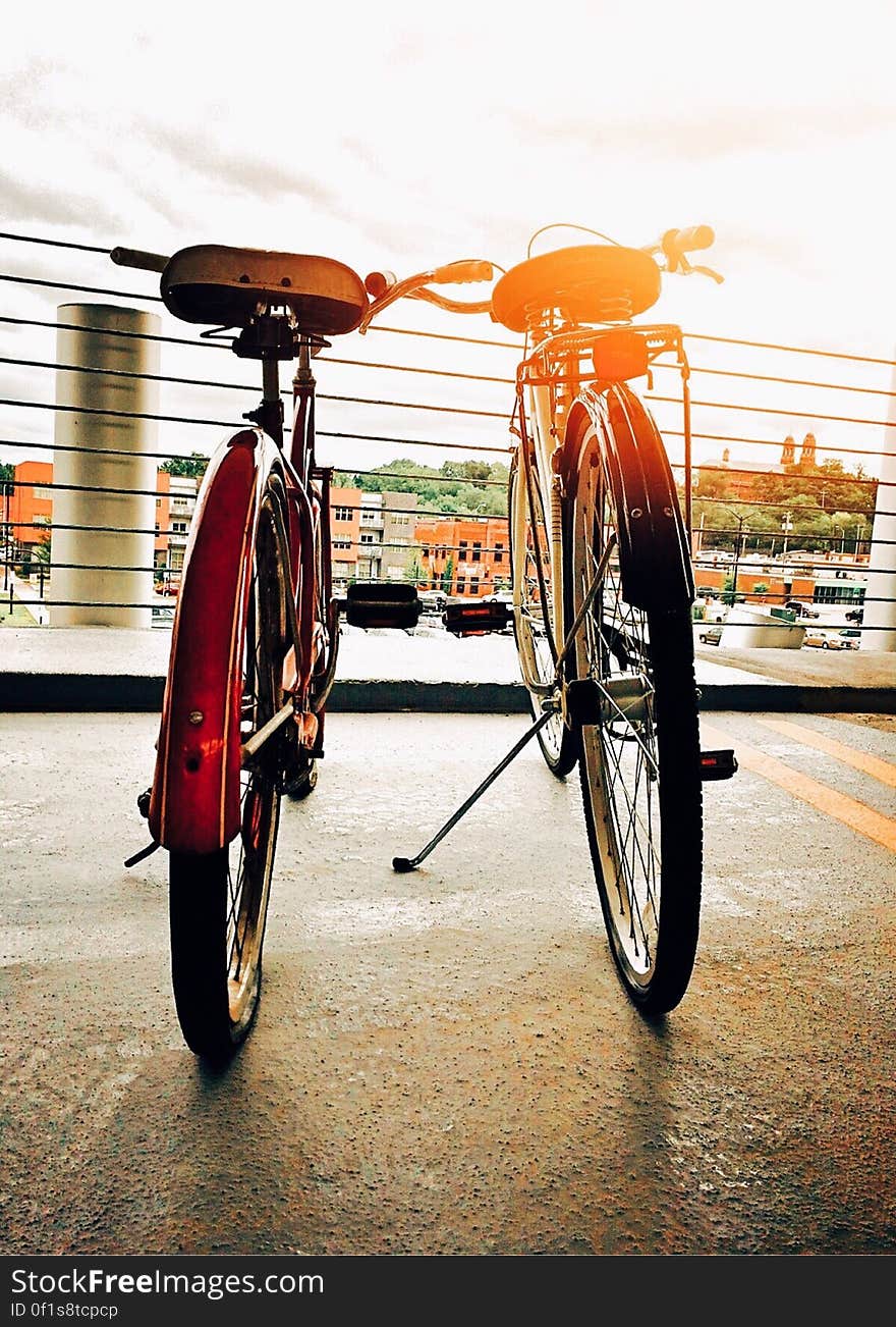 Two bicycles parked side by side in city with bright sun flare. Two bicycles parked side by side in city with bright sun flare.