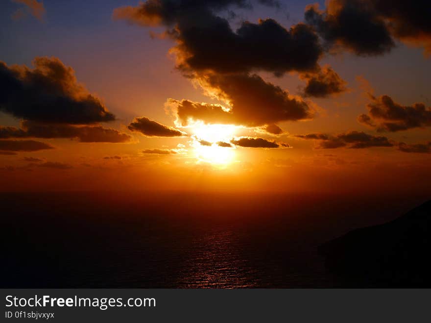 Cloudscape over calm sea with bright orange sunset. Cloudscape over calm sea with bright orange sunset.