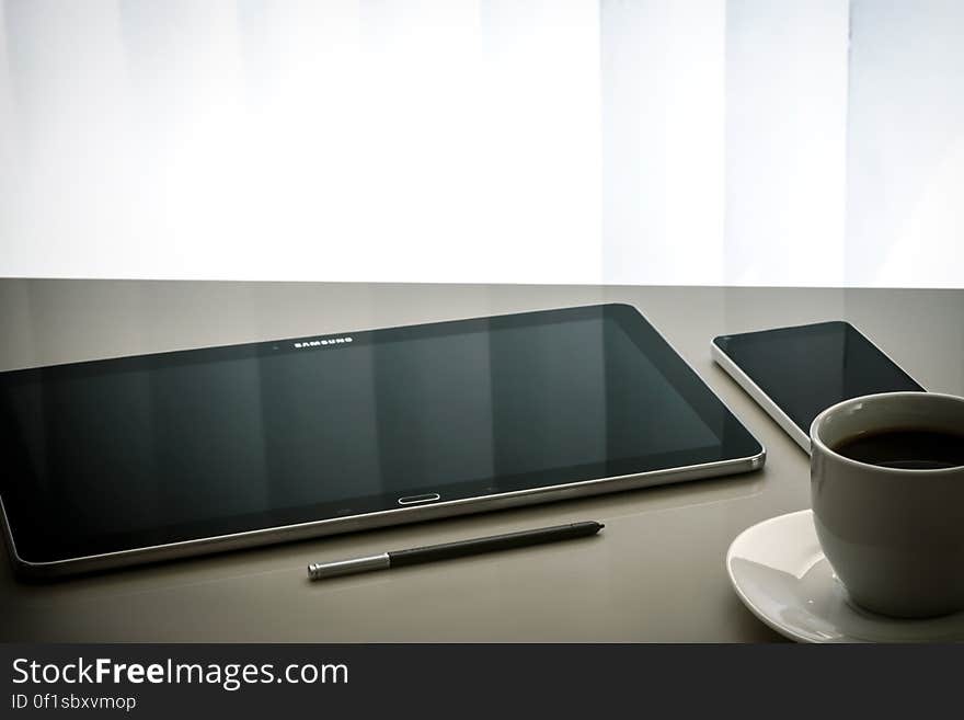 Tablet, smartphone, pencil and a cup of coffee on a table. Tablet, smartphone, pencil and a cup of coffee on a table.