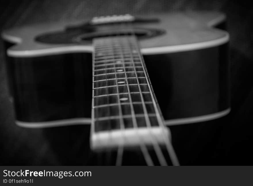 A black and white close up of an acoustic guitar.