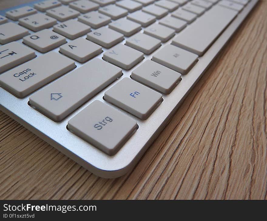 White Computer Keyboard on Brown Wooden Table